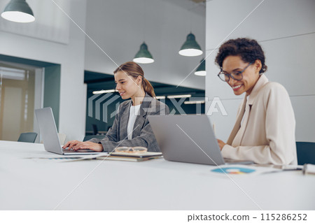 Young stylish female sales managers working together in a coworking office Young stylish female sales managers working together in a coworking office 115286252