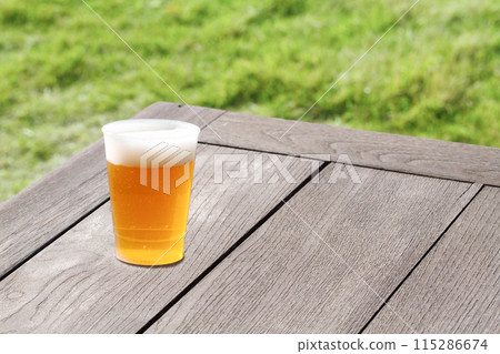 Beer on a vintage wooden table. The grass is vibrant and makes for a refreshing summer drink. 115286674
