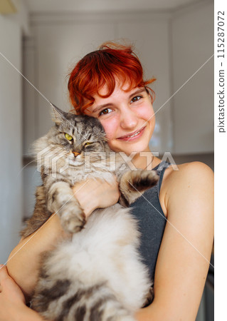 portrait red-haired teenage girl with gray fluffy cat 115287072