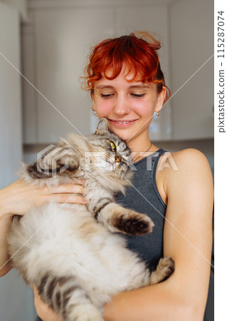 portrait red-haired teenage girl with gray fluffy cat 115287074