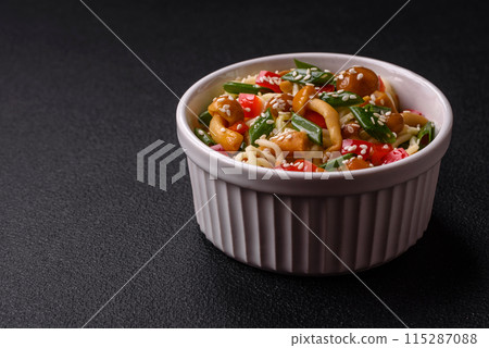 Delicious Asian cuisine dish with rice noodles, peppers, mushrooms and spices Delicious Asian cuisine dish with rice noodles, peppers, mushrooms and spices 115287088