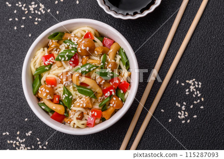 Delicious Asian cuisine dish with rice noodles, peppers, mushrooms and spices Delicious Asian cuisine dish with rice noodles, peppers, mushrooms and spices 115287093