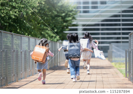 Back view of elementary school students with backpacks running energetically to and from school. Multiple full-body images without faces. 115287894