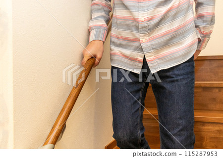 一個人扶著扶手走下樓梯 一個人扶著扶手走下樓梯 115287953