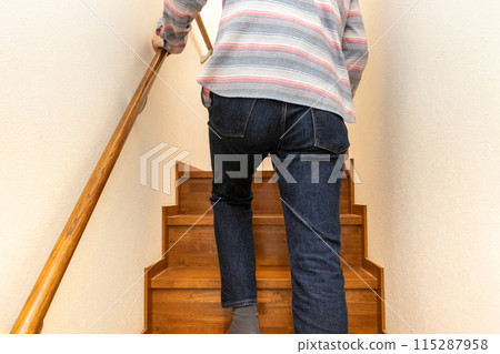 一個男人扶著扶手爬樓梯的後視圖 115287958