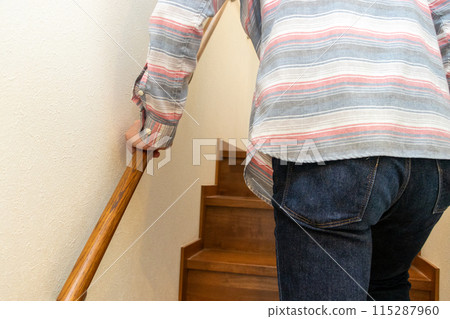 A man walking up the stairs holding onto the banister A man walking up the stairs holding onto the banister 115287960
