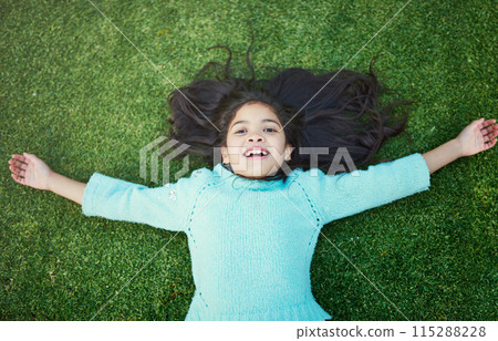 Child, grass and portrait with smile for resting in park on weekend with top view in nature or garden. Development, preteen and green in summer with backyard or vacation in childhood with freedom. Child, grass and portrait with smile for resting in park on weekend with top view in nature or garden. Development, preteen and green in summer with backyard or vacation in childhood with freedom. 115288228