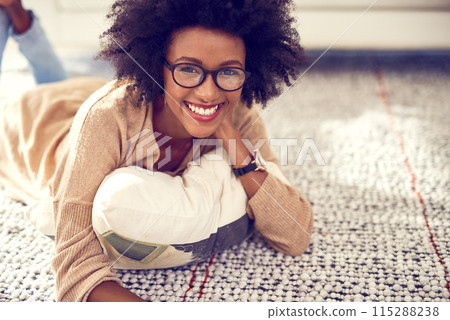 Portrait, black woman and relax on floor at home on carpet for break or peace with smile for weekend to chill on living room. Happy, African and female person with glasses for resting at apartment 115288238