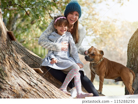 Happy mother, child and dog with hug for bonding and quality time outside in nature on winter break. Family, woman and girl with pet for love embrace, relax together and vacation with sunshine 115288250