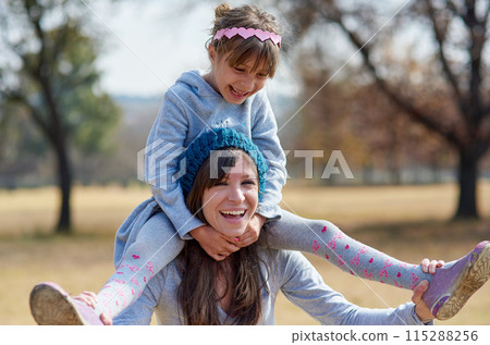 Funny, mother and piggyback child at park, laughing and family bonding together in nature on holiday. Happy girl, mom and carry kid at garden in summer for love, connection and support of parent 115288256