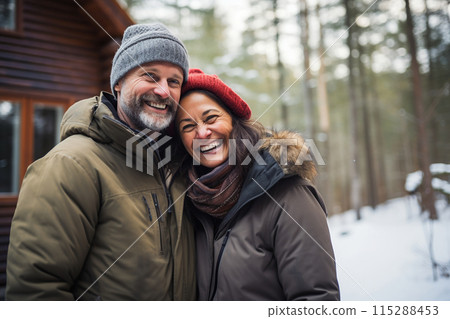 Joyful man and woman in cold weather clothing stand before a winter lodge Joyful man and woman in cold weather clothing stand before a winter lodge 115288453