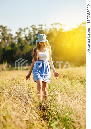 Woman, walking and happiness in nature for field, travel and adventure in countryside for spring. Gen z, smile and journey in natural environment with flowers, leaves and sun on holiday in France 115288630
