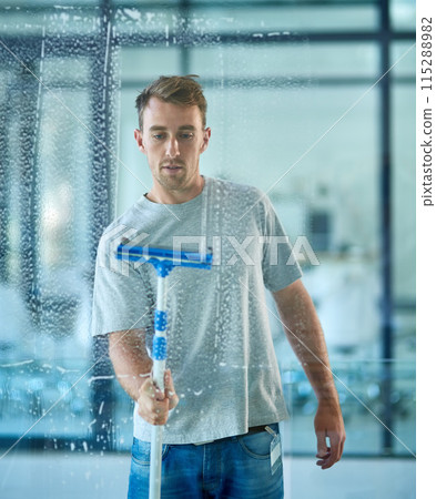 Man, cleaning and window in office building as janitor with squeegee tool for hygiene service, glass or bacteria. Male person, soap and disinfection in corporate workplace or washing, dust or germs 115288982