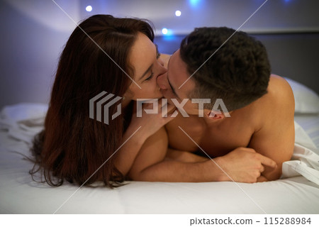 Couple, kiss and love in bed for relax, affection and embrace for intimate moment in home. Sexual, sexy and foreplay together in house, nude and skin for connection between man and woman in bedroom 115288984