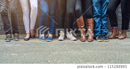 People, legs and shoes in row with against wall for fashion, style and outfit in streets of New York. Group, friends and together with footwear for trends, casual wear and chill or relax outdoor 115288985
