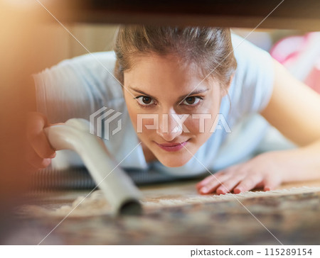Woman, vacuum and cleaning carpet floor in home for hygiene, housework or housekeeping service in living room. Chores, maid and electrical machine to remove dirt, dust and bacteria with face closeup 115289154
