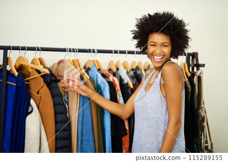 Woman, portrait and rack of clothes in home with smile for fashion, choice and excited to start morning. Girl, person and happy with style, decision and ready for routine by wardrobe in apartment Woman, portrait and rack of clothes in home with smile for fashion, choice and excited to start morning. Girl, person and happy with style, decision and ready for routine by wardrobe in apartment 115289155