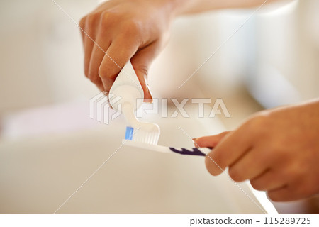 Toothpaste, hands and brush for dental health in bathroom with morning hygiene routine at home. Clean, wellness and person with oral care products for plaque, gums and fresh breath treatment at home. 115289725