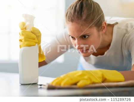 Woman, kitchen spray and cleaning table in home for hygiene, housework or housekeeping service for safety. Chores, bottle and maid with cloth on counter to wipe dirt, dust and bacteria in apartment 115289726