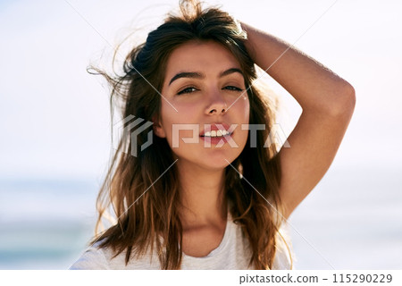 Woman, beach and portrait in sun on vacation, holiday and travel in Brazil. Holding hair, coast and beautiful person near ocean for harmony, relaxation and calm in sunshine for time off on shoreline 115290229