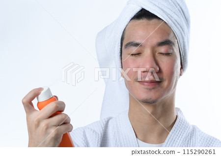 Young man spraying sunscreen on his face. UV protection and aesthetic face treatment concept 115290261
