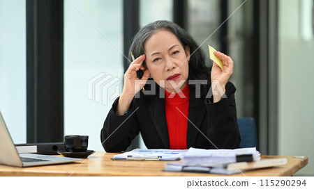 Mature businesswoman feeling unwell, suffering from migraine headache at workplace Mature businesswoman feeling unwell, suffering from migraine headache at workplace 115290294