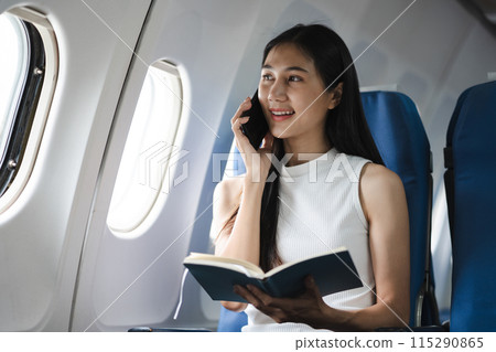 Waist up image of a fun business woman in an airline working on his computer while talking on a cell phone. Waist up image of a fun business woman in an airline working on his computer while talking on a cell phone. 115290865