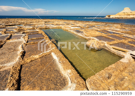 Traditional salt pans in Xwejni Bay on the beach of island of Gozo, Malta. Traditional salt pans in Xwejni Bay on the beach of island of Gozo, Malta. 115290959