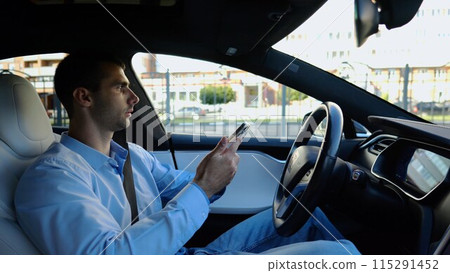 Male businessperson have serious telephone conversation while riding an autonomous self driving electric car. Nervous businessman talks by smartphone during riding on electrical auto with autopilot 115291452