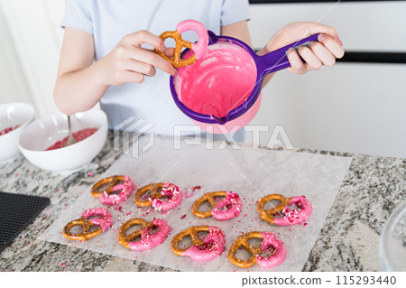 Freshly dipped and still glistening, these crunchy pretzels are lovingly adorned with pink chocolate and a scattering of colorful sprinkles, promising a feast for the senses. 115293440