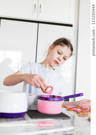 With focused attention, this budding culinary artist dips pretzels into a pot of melted chocolate, creating sweet delights in the warmth of a well-lit home kitchen. With focused attention, this budding culinary artist dips pretzels into a pot of melted chocolate, creating sweet delights in the warmth of a well-lit home kitchen. 115293444
