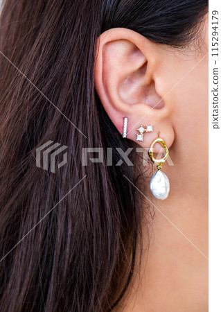Young woman wearing pearl earrings and stud earrings with zirconia. 115294179