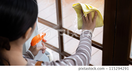 High angle view of female cleaner wiping window with yellow cloth. Concept of home cleanliness High angle view of female cleaner wiping window with yellow cloth. Concept of home cleanliness 115294291