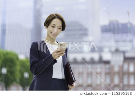 拿著筆記本和操作智慧型手機的女商人 115295198