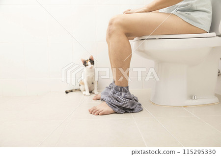 Close up view of man sitting on toilet bowl in rest room 115295330