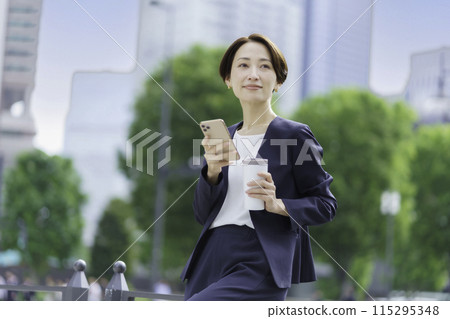 手裡拿著不倒翁和智慧型手機的女商人 115295348