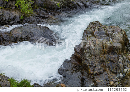 Scenery of a clear stream flowing over rocks on a rainy day 115295362