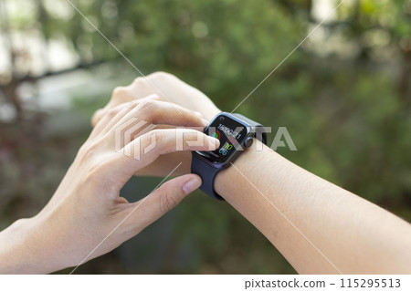 Woman uses the smartwatch to check the latest notifications and messages outside Woman uses the smartwatch to check the latest notifications and messages outside 115295513