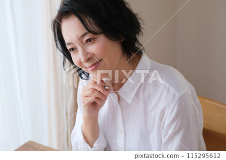 A middle-aged woman writing a letter to her family in the living room 115295612