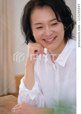 A middle-aged woman writing a letter to her family in the living room A middle-aged woman writing a letter to her family in the living room 115295645
