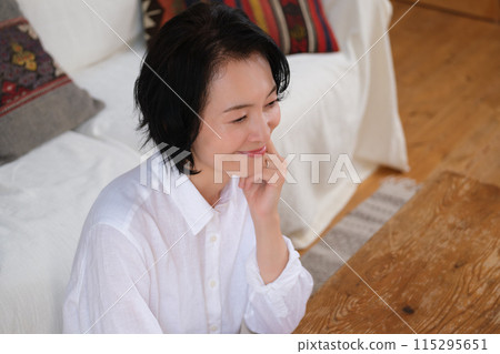 A middle-aged woman writing a letter to her family in the living room A middle-aged woman writing a letter to her family in the living room 115295651