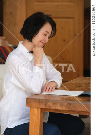 A middle-aged woman writing a letter to her family in the living room A middle-aged woman writing a letter to her family in the living room 115295664