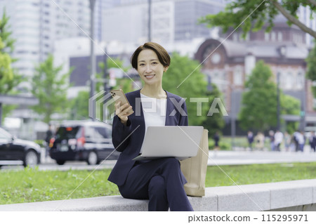 Portrait of a businesswoman in an office district holding a laptop and smartphone Portrait of a businesswoman in an office district holding a laptop and smartphone 115295971