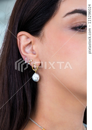 Young woman wearing pearl earrings and stud earrings with zirconia. 115296024