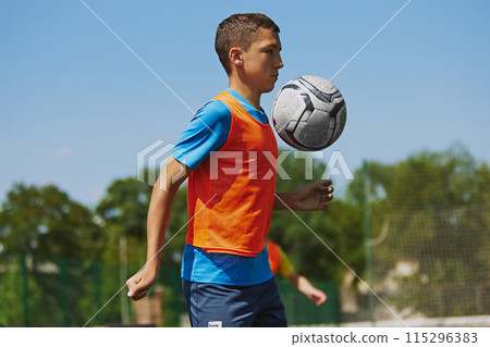Focused and concentrated boy in colorful sportswear in motion, practicing soccer game outdoor, hitting ball with chest. Focused and concentrated boy in colorful sportswear in motion, practicing soccer game outdoor, hitting ball with chest. 115296383