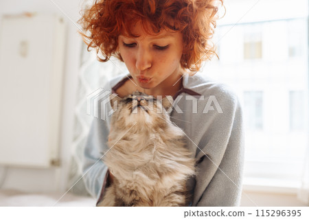 Portrait red-haired curly young woman with beloved fluffy domestic cat 115296395