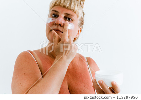 Middle-aged woman applying after-sun cream Middle-aged woman applying after-sun cream 115297950
