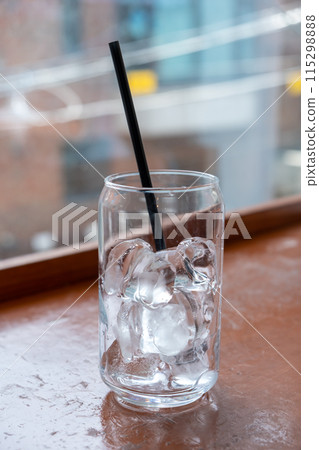 A can-shaped glass of ice with the straw on the table with bokeh background A can-shaped glass of ice with the straw on the table with bokeh background 115298888