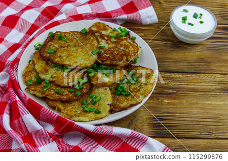 Potato pancakes with sour cream on a wooden table 115299876
