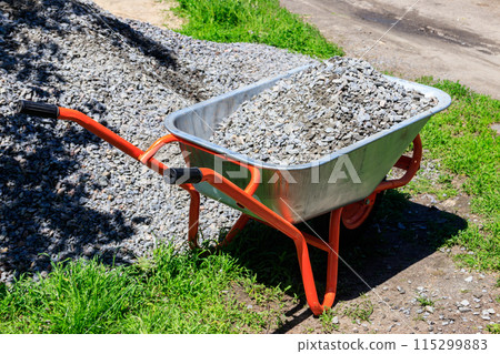 Wheelbarrow with gravel at the construction site 115299883